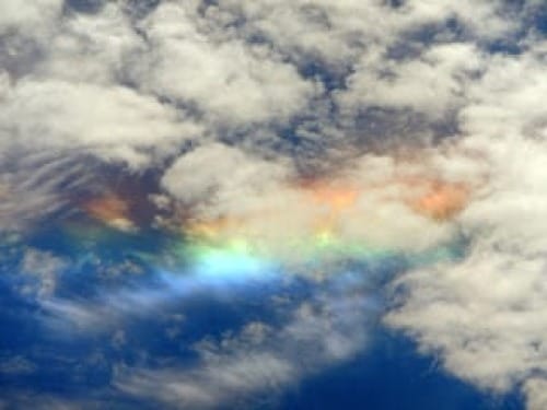 Photo of 'sundog' rainbow like colors streaked through clouds.