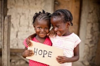 Photo of two little girls from a region in Africa holding a sign that says 'hope.'