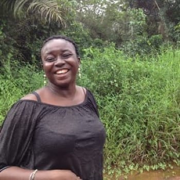 Photo of woman named Fataba smiling on a road in the Sierra Leone rainforest.