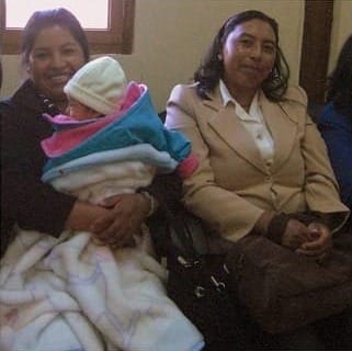Photo of two Ecuadorian women, one holding a bundled-up baby.