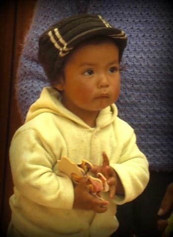 Photo of Ecuadorian toddler in bright hello outfit and khaki cap.