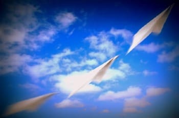 Photo of 3 paper airplances gliding up into blue sky and clouds.