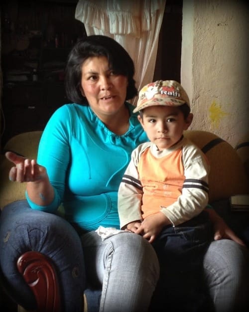 Photo of Ecuadorian mother and her young son on her lap in her livingroom.
