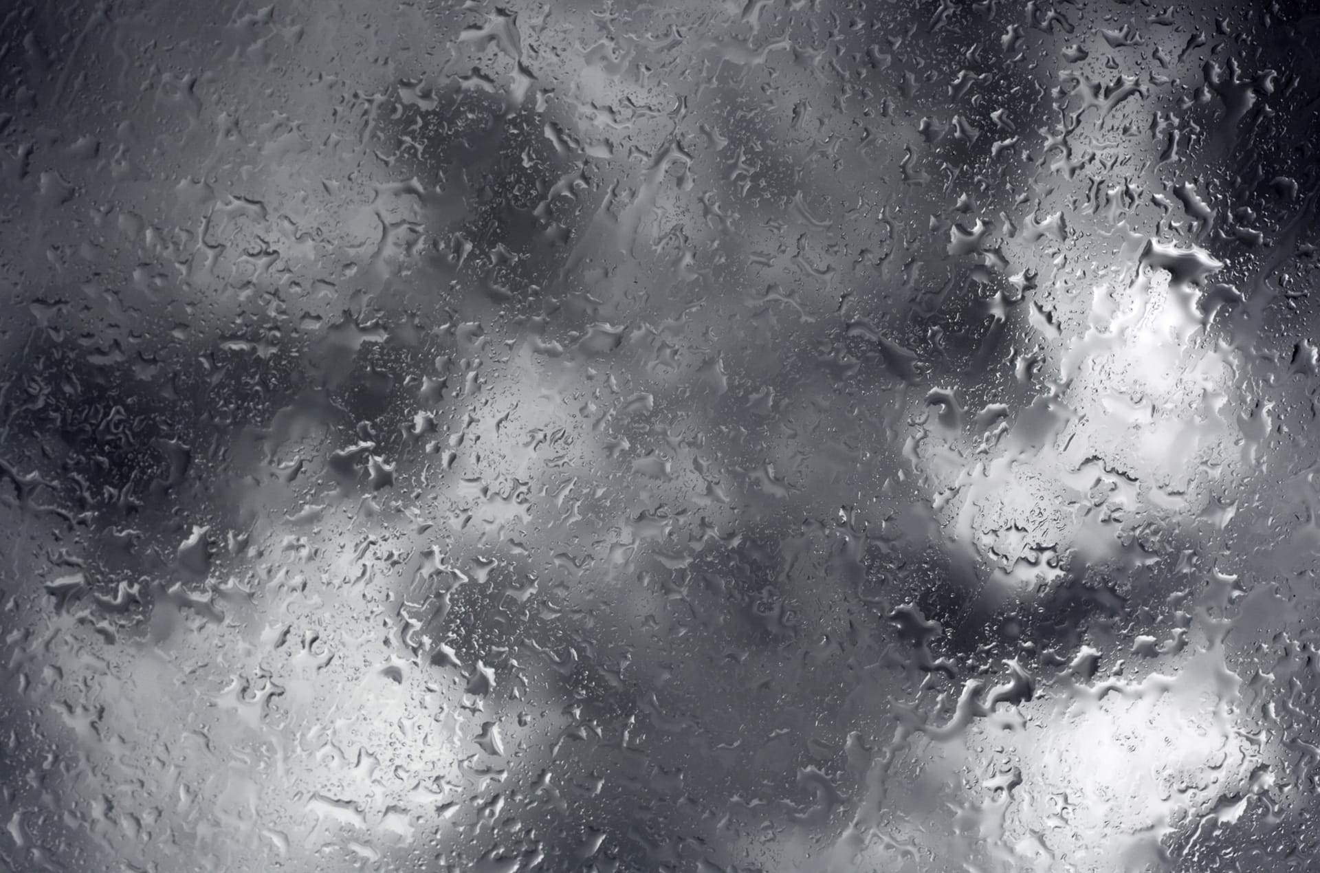 Photo, black & white, of rain and clouds reflected on glass
