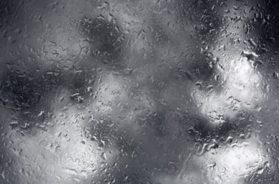 Photo, black & white, of rain and clouds reflected on glass