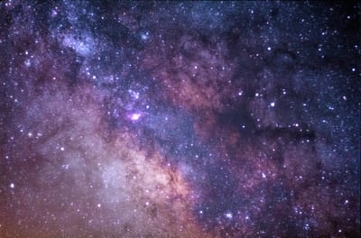 Photo of deep night sky studded with stars on a purple-magenta background