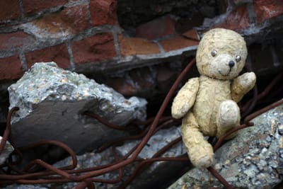 Soiled teddy bear among rubble of concrete and wires