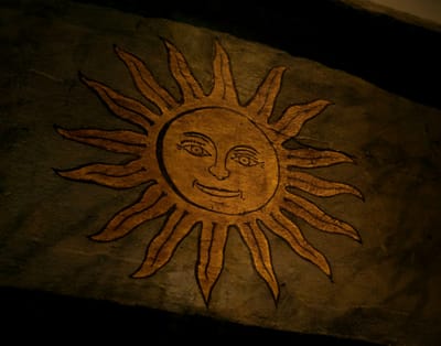 Image of illustration of sun with smiling face painted on wood.